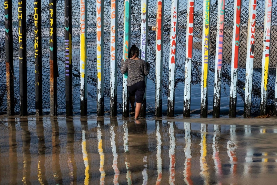 La gente camina cerca de la valla fronteriza entre México y Estados Unidos en Playas de Tijuana, México. El presidente Donald Trump advirtió el miércoles pasado que el gobierno federal de los EE. UU. se mantiene firme en su deseo de reforzar el muro fronterizo con México.