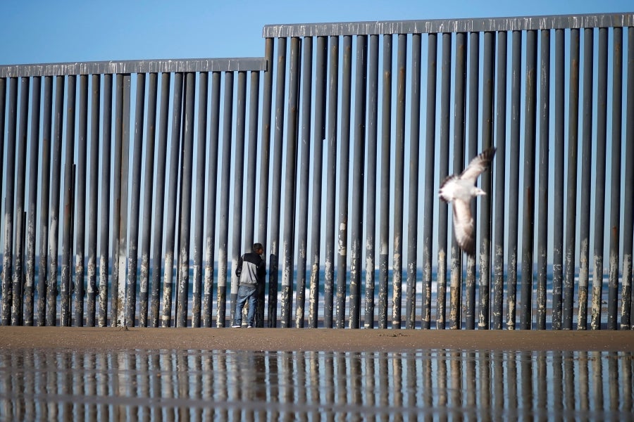 La gente camina cerca de la valla fronteriza entre México y Estados Unidos en Playas de Tijuana, México. El presidente Donald Trump advirtió el miércoles pasado que el gobierno federal de los EE. UU. se mantiene firme en su deseo de reforzar el muro fronterizo con México.