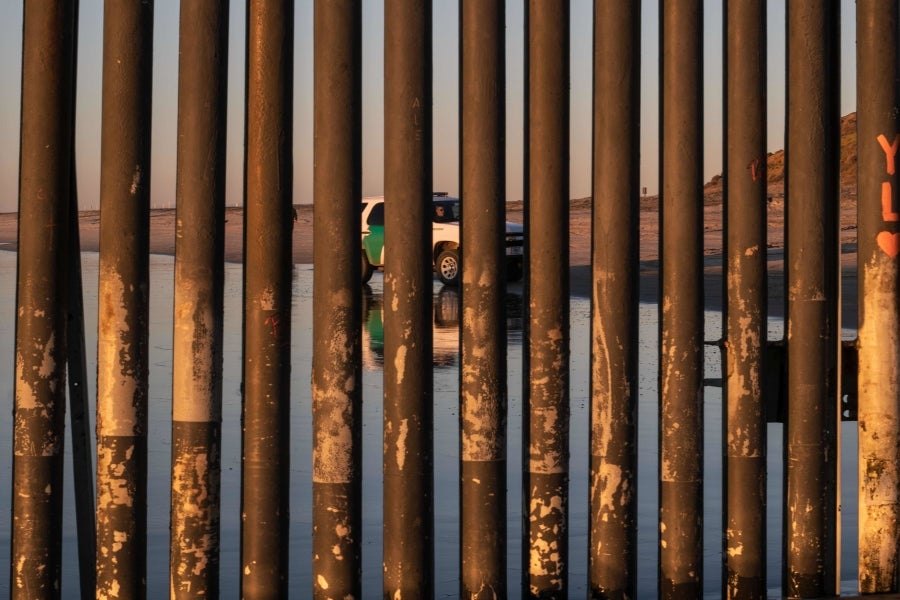 La gente camina cerca de la valla fronteriza entre México y Estados Unidos en Playas de Tijuana, México. El presidente Donald Trump advirtió el miércoles pasado que el gobierno federal de los EE. UU. se mantiene firme en su deseo de reforzar el muro fronterizo con México.