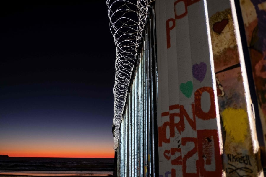 La gente camina cerca de la valla fronteriza entre México y Estados Unidos en Playas de Tijuana, México. El presidente Donald Trump advirtió el miércoles pasado que el gobierno federal de los EE. UU. se mantiene firme en su deseo de reforzar el muro fronterizo con México.