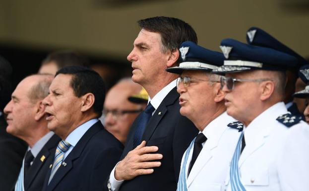 Bolsonaro y el vicepresidente Mourao entonan el himno nacional durante la ceremonia de toma de mando del teniente brigadier Moretti.