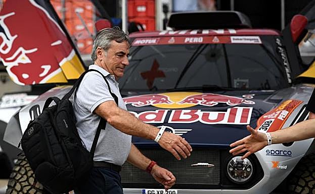 Carlos Sainz saluda a un miembro de su equipo delante del coche con el que competirá en el Dakar.