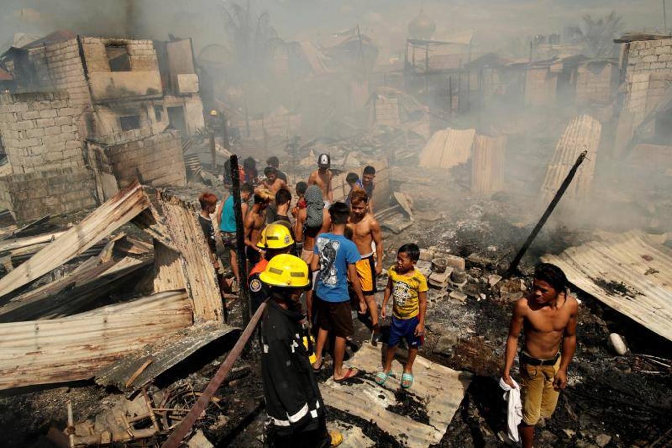 Residentes se afanan por apagar las llamas durante el incendio originado en un barrio de chabolas de Manila, en Filipinas, hoy, 11 de enero de 2019. El incendio destrozó las viviendas de al menos 100 familias pobres.