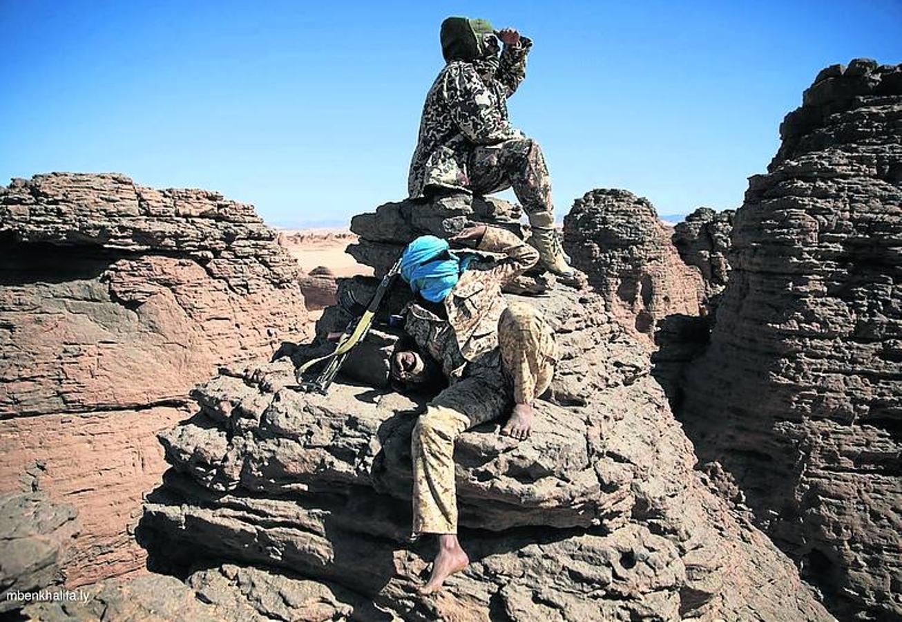 Soldados libios montan guardia sobre una roca en el desierto bajo temperaturas extremas.