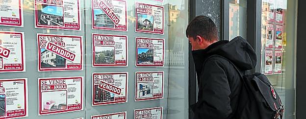Un joven observa la oferta de viviendas de una inmobiliaria en Irun.