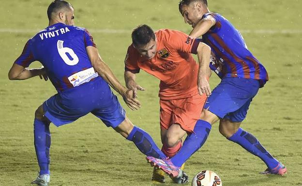 Loukas Vyntra (i) y Toño García, defensas del Levante, derriban a Leo Messi. 