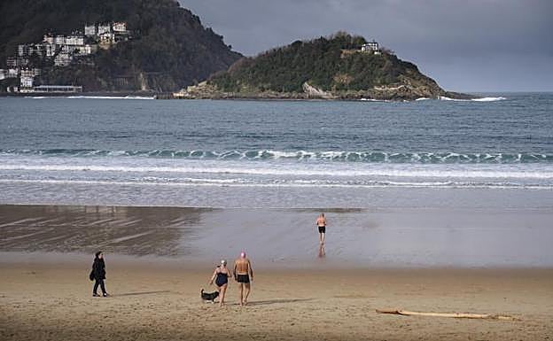 Tres bañistas se dirigen al agua para darse un chapuzón ayer en la playa de La Concha.