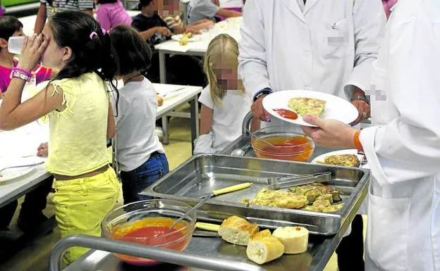 Una trabajadora de una empresa de catering reparte la comida en un colegio público. 