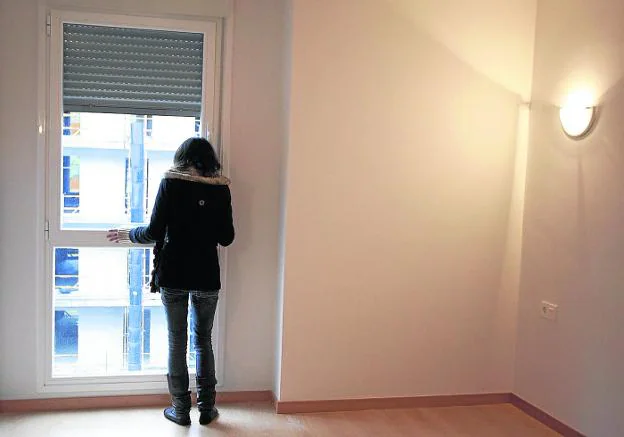 Adjudicataria de un piso social mira por la ventana tras entrar por primera vez en la vivienda.