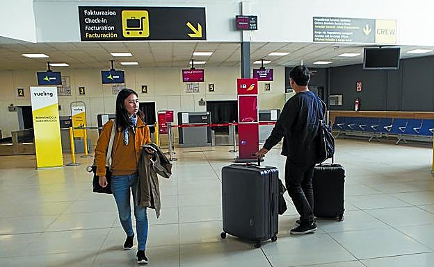 Dos viajeros, por la tarde, en la terminal vacía de Hondarribia, con los mostradores de facturación cerrados. 