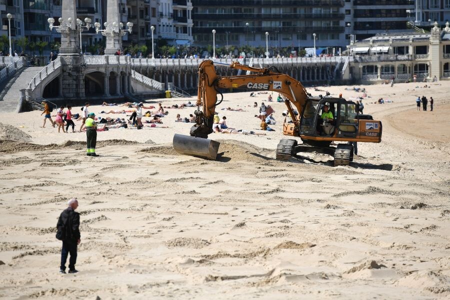 Las excavadoras trabajan ya en las playas donostiarras realizando trabajos de explanación de la arena para poder instalar posteriormente los servicios para el verano (toldos, cafetería, etcétera).
