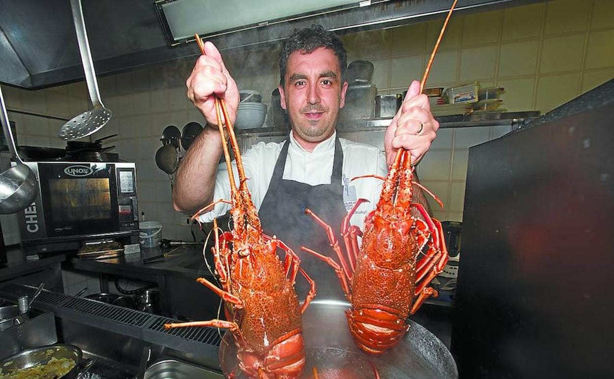 Aitor, que capitanea junto a Jon el Arraunlari Berri, posa con dos langostas en la cocina del restaurante.