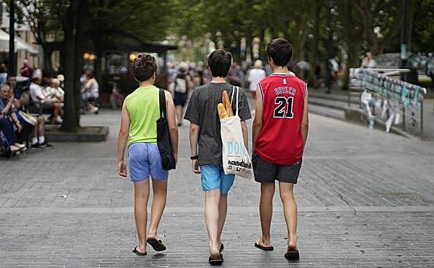 Tres jóvenes realizan la compra con una bolsa de tela en uno de los puestos de frutas y verduras en el exterior del mercado de la Bretxa de Donostia. 