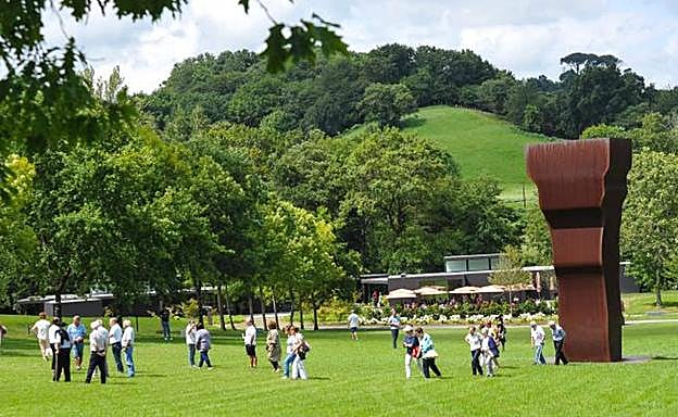 Un grupo de visitantes recorre la campa de Zabalaga, junto a la escultura 'Buscando la luz I', el pasado jueves. 