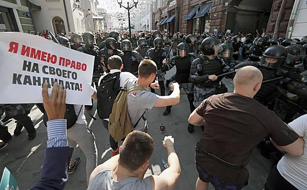 Un manifestante lleva un cartel que dice: «¡Tengo derecho a mi propio candidato!», Mientras la policía antidisturbios rusa dispersa a una multitud de activistas de la oposición durante una protesta.