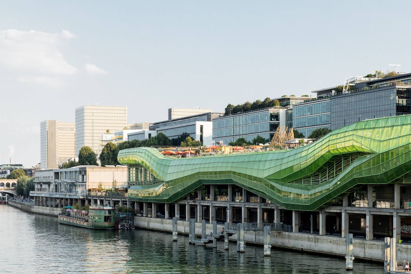 Ciudad de la Moda y el Diseño, París (Francia). Este llamativo edificio se encuentra junto a las orillas del río Sena. Diseñada por la firma local Jakob + MacFarlane, el proyecto transformó unos antiguos almacenes. Los arquitectos mantuvieron la estructura de cemento e incorporaron una estructura de metal y cristal, en un color verde brillante, que 'simula' el movimiento del río. La iluminación, diseñada por el artista Yann Kersalé, pone un punto de color todas las noches.