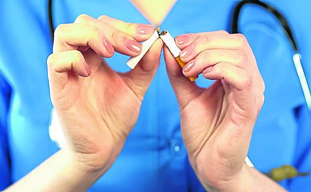 Un médico parte en dos un cigarrillo, un símbolo de la necesidad de romper con el hábito.