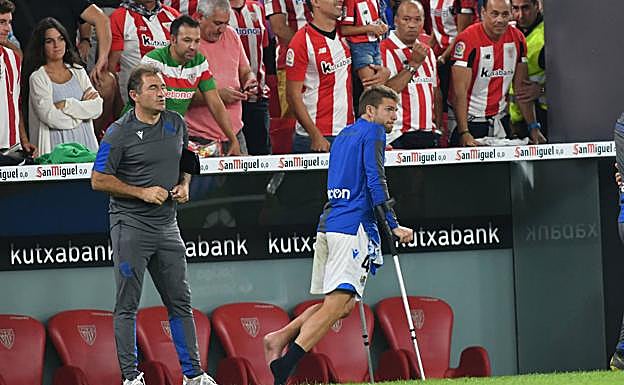 Asier Illarramendi camina con muletas en la banda de San Mamés tras caer lesionado a la media hora de partido. A su lado, Luis Llopis.