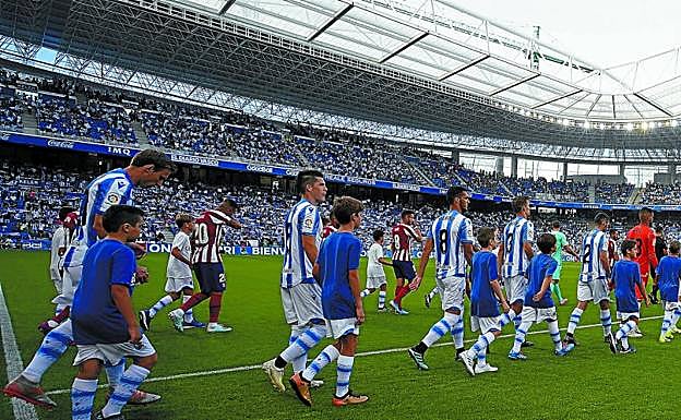 Los jugadores de la Real y los del Atlético saltan al estadio donostiarra, con el nuevo fondo norte a la derecha y un gran ambiente en las gradas.