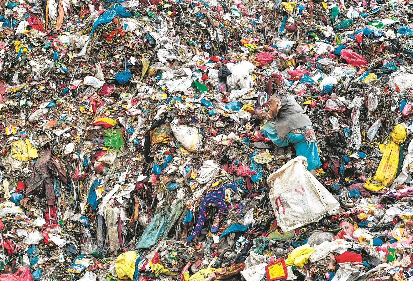 Una descomunal montaña de basura hace invisible a una mujer en Sisdol, Nepal.