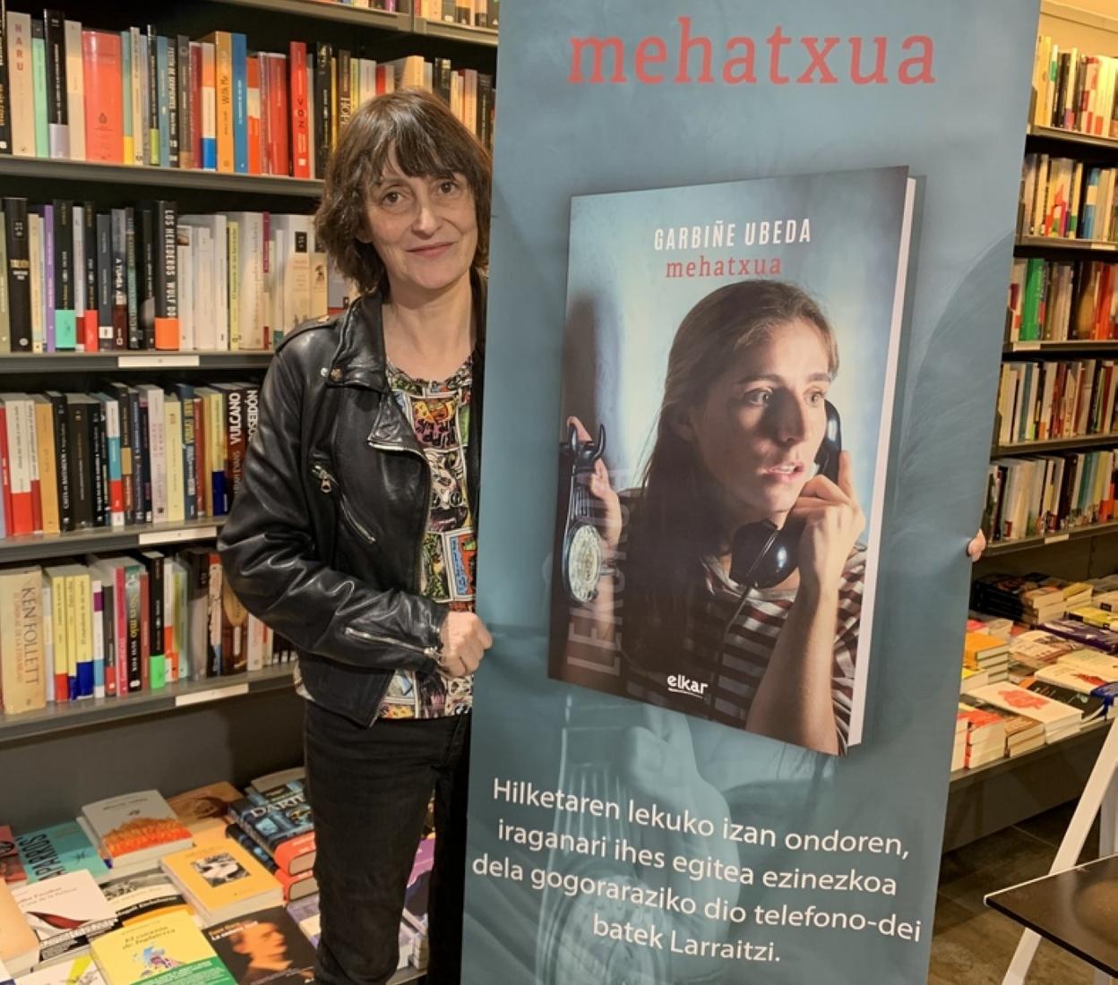 Garbiñe Ubeda, liburuaren azala erakusten duen kartelarekin. 