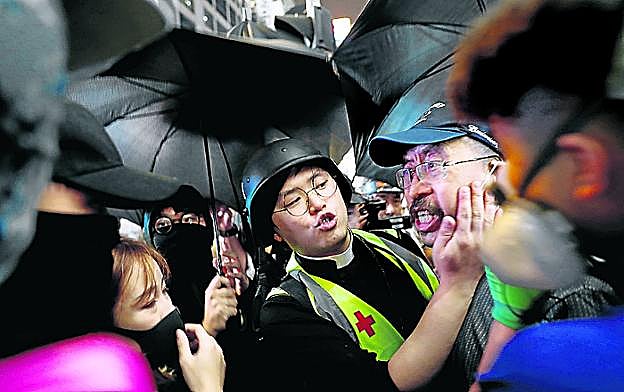  Ayuda. Keung alivia con su espray a un manifestante afectado por el gas, consuela a un sanitario y tranquiliza a un transeúnte molesto por las protestas. 