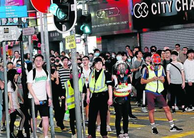 Imagen secundaria 1 - Arriba, Keung acaricia a un niño en su Iglesia, abajo, Alan Keung, en medio de los manifestantes, listo para actuar.