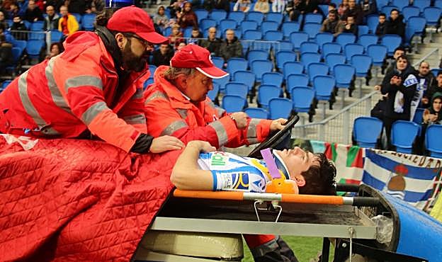 Aritz Elustondo es retirado del campo en camilla, con un collarín, por voluntarios de Cruz Roja. 