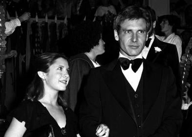 Imagen secundaria 1 - Luis Gasca, el director que trajo a Donostia el estreno de 1977, brinda con una taza de marketing de la saga. Carrie Fisher y Harrison Ford a la entrada del Victoria Eugenia en el histórico pase de 1977.. Oscar Isaac, protagonista de la última entrega de la saga, asiste a la presentación de la película en Tokio, acompañado de los 'soldados' imperiales.