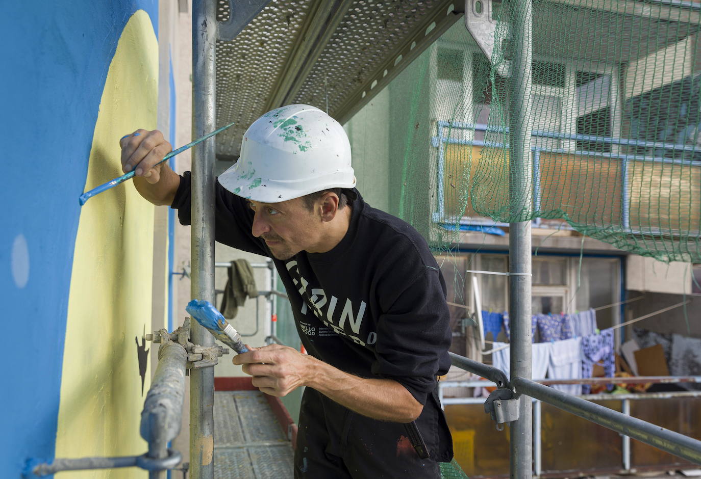 Los miembros del grupo Szines Varos (ciudad colorida) trabajan en un andamio para crear un mural en un edificio residencial en el Distrito VIII de Budapest. La obra de arte de 600 metros cuadrados representa a los personajes principales de la popular caricatura húngara Macskafogo (lit. Cat Catcher) de 1986, que se distribuyó como 'cat city' en Estados Unidos. El colectivo artístico ha realizado muchos murales a gran escala en Budapest y otras ciudades húngaras, así como en Moscú, Berlín y Londres, desde su fundación en 2008.