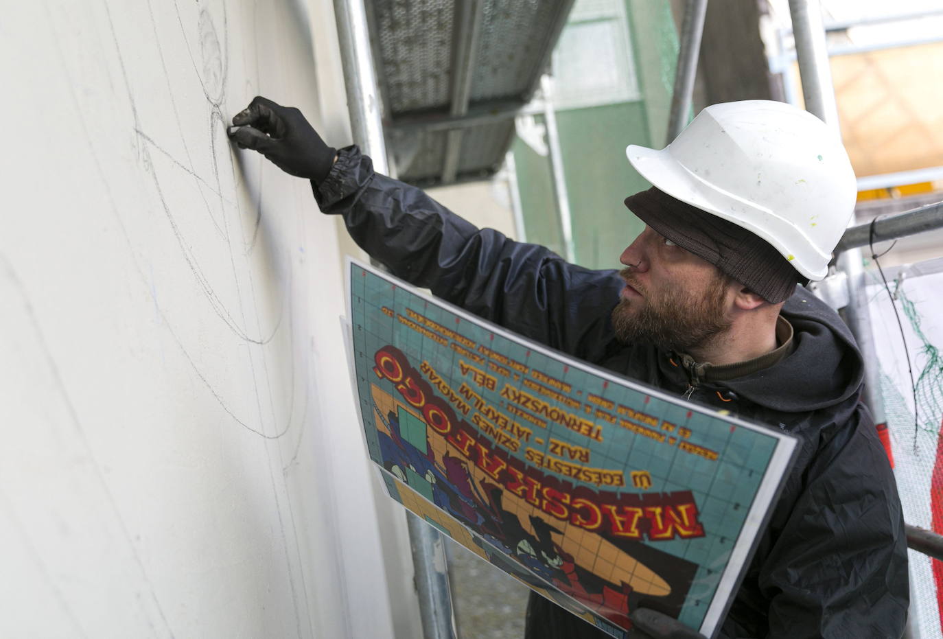 Los miembros del grupo Szines Varos (ciudad colorida) trabajan en un andamio para crear un mural en un edificio residencial en el Distrito VIII de Budapest. La obra de arte de 600 metros cuadrados representa a los personajes principales de la popular caricatura húngara Macskafogo (lit. Cat Catcher) de 1986, que se distribuyó como 'cat city' en Estados Unidos. El colectivo artístico ha realizado muchos murales a gran escala en Budapest y otras ciudades húngaras, así como en Moscú, Berlín y Londres, desde su fundación en 2008.