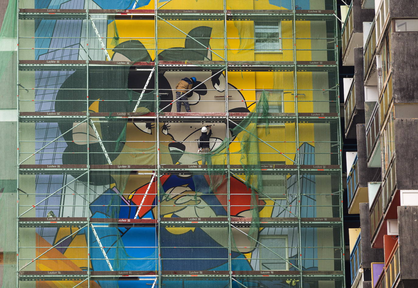 Los miembros del grupo Szines Varos (ciudad colorida) trabajan en un andamio para crear un mural en un edificio residencial en el Distrito VIII de Budapest. La obra de arte de 600 metros cuadrados representa a los personajes principales de la popular caricatura húngara Macskafogo (lit. Cat Catcher) de 1986, que se distribuyó como 'cat city' en Estados Unidos. El colectivo artístico ha realizado muchos murales a gran escala en Budapest y otras ciudades húngaras, así como en Moscú, Berlín y Londres, desde su fundación en 2008.