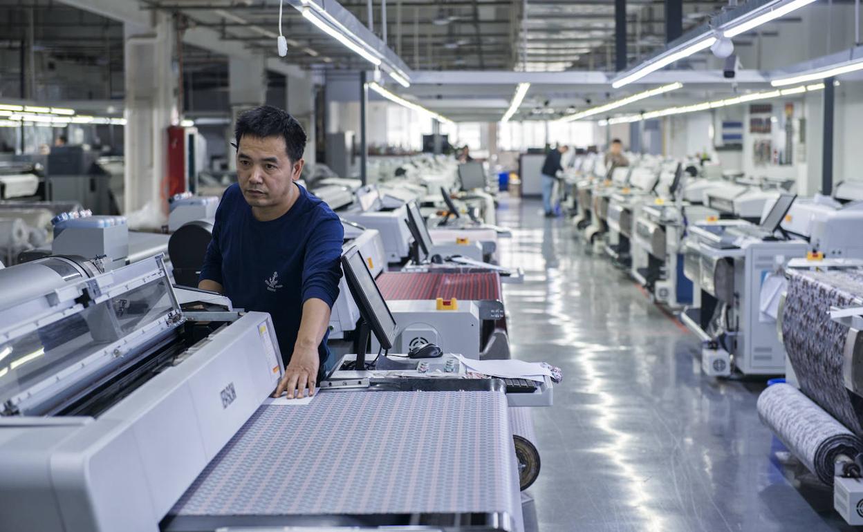 Un operario revisa la producción de una fábrica de tejidos en Hangzhou, China.