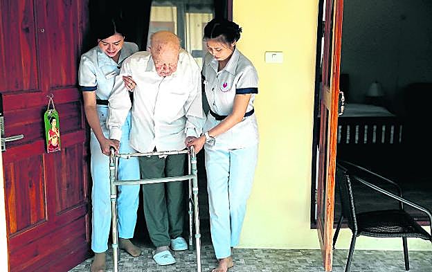 Wolfgang, de 96 años, es ayudado por dos enfermeras tailandensas del complejo Care Resort, en Chiang Mai.