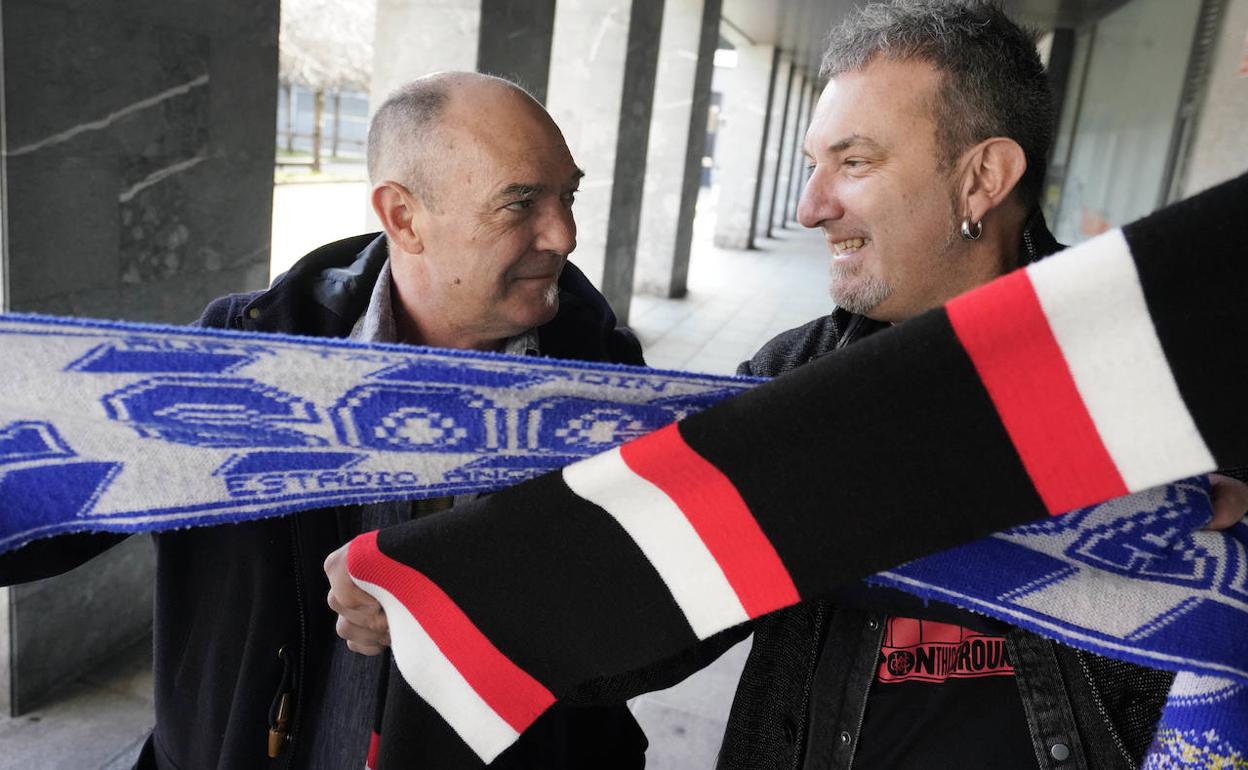 Andoni Egañak eta Jon Maiak euren begiradak gurutzatzen dituzte bakoitzaren kolore kutunak adierazten dituzten bufandak hartuta, Donostiako kale batean derbiaren atarian.