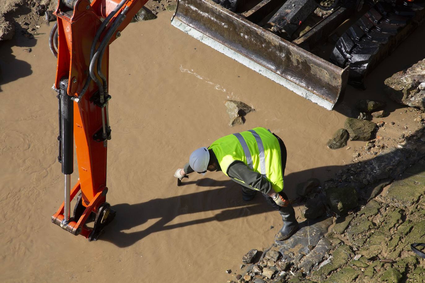 La playa de La Concha se ha convertido en la bajamar de este lunes por la mañana en un inesperado yacimiento arqueológico. La presencia de una pequeña excavadora retirando piedras y escombros junto al muro de costa a la altura del edificio consistorial ha suscitado una gran expectación entre los numerosos viandantes y turistas que han provechado el buen tiempo para dar un paseo. La máquina profundizaba en la arena en busca de los restos de un barco hundido del que hay constancia documental desde el siglo XVIII. 