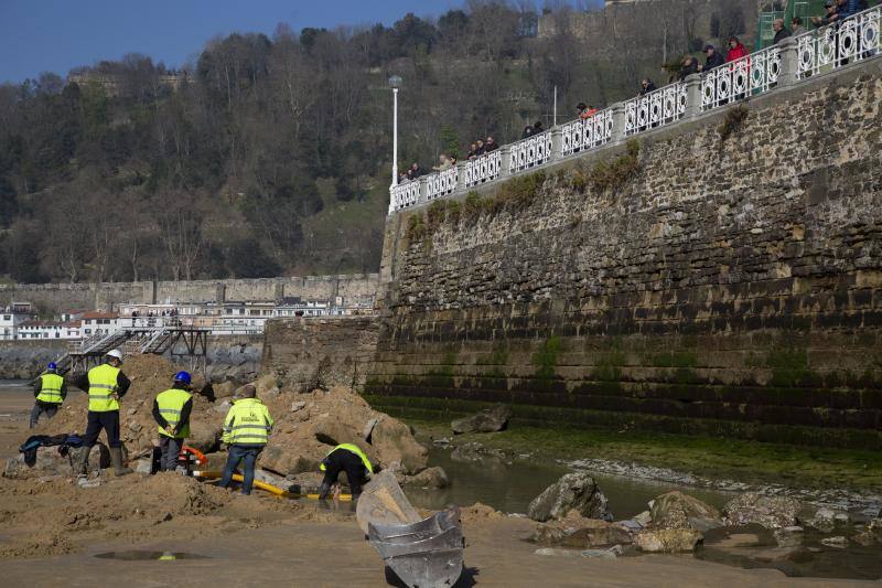 La playa de La Concha se ha convertido en la bajamar de este lunes por la mañana en un inesperado yacimiento arqueológico. La presencia de una pequeña excavadora retirando piedras y escombros junto al muro de costa a la altura del edificio consistorial ha suscitado una gran expectación entre los numerosos viandantes y turistas que han provechado el buen tiempo para dar un paseo. La máquina profundizaba en la arena en busca de los restos de un barco hundido del que hay constancia documental desde el siglo XVIII. 
