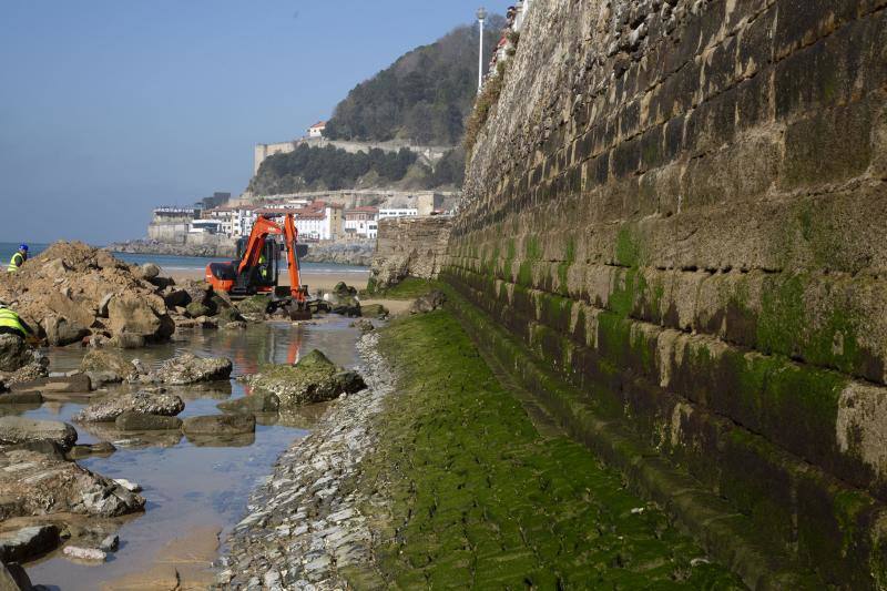 La playa de La Concha se ha convertido en la bajamar de este lunes por la mañana en un inesperado yacimiento arqueológico. La presencia de una pequeña excavadora retirando piedras y escombros junto al muro de costa a la altura del edificio consistorial ha suscitado una gran expectación entre los numerosos viandantes y turistas que han provechado el buen tiempo para dar un paseo. La máquina profundizaba en la arena en busca de los restos de un barco hundido del que hay constancia documental desde el siglo XVIII. 