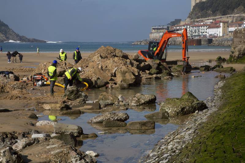 La playa de La Concha se ha convertido en la bajamar de este lunes por la mañana en un inesperado yacimiento arqueológico. La presencia de una pequeña excavadora retirando piedras y escombros junto al muro de costa a la altura del edificio consistorial ha suscitado una gran expectación entre los numerosos viandantes y turistas que han provechado el buen tiempo para dar un paseo. La máquina profundizaba en la arena en busca de los restos de un barco hundido del que hay constancia documental desde el siglo XVIII. 