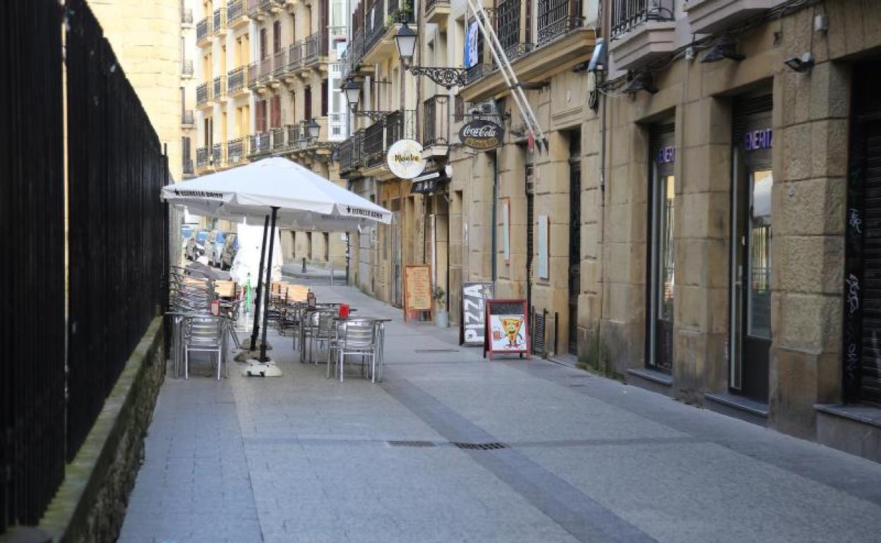 Vista de una calle de la Parte Vieja donostiarra con la terraza de un bar vacía.