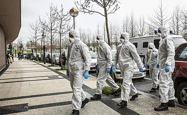 Agentes de la Ertzaintza entregan órdenes de confinamiento en un portal de Vitoria.