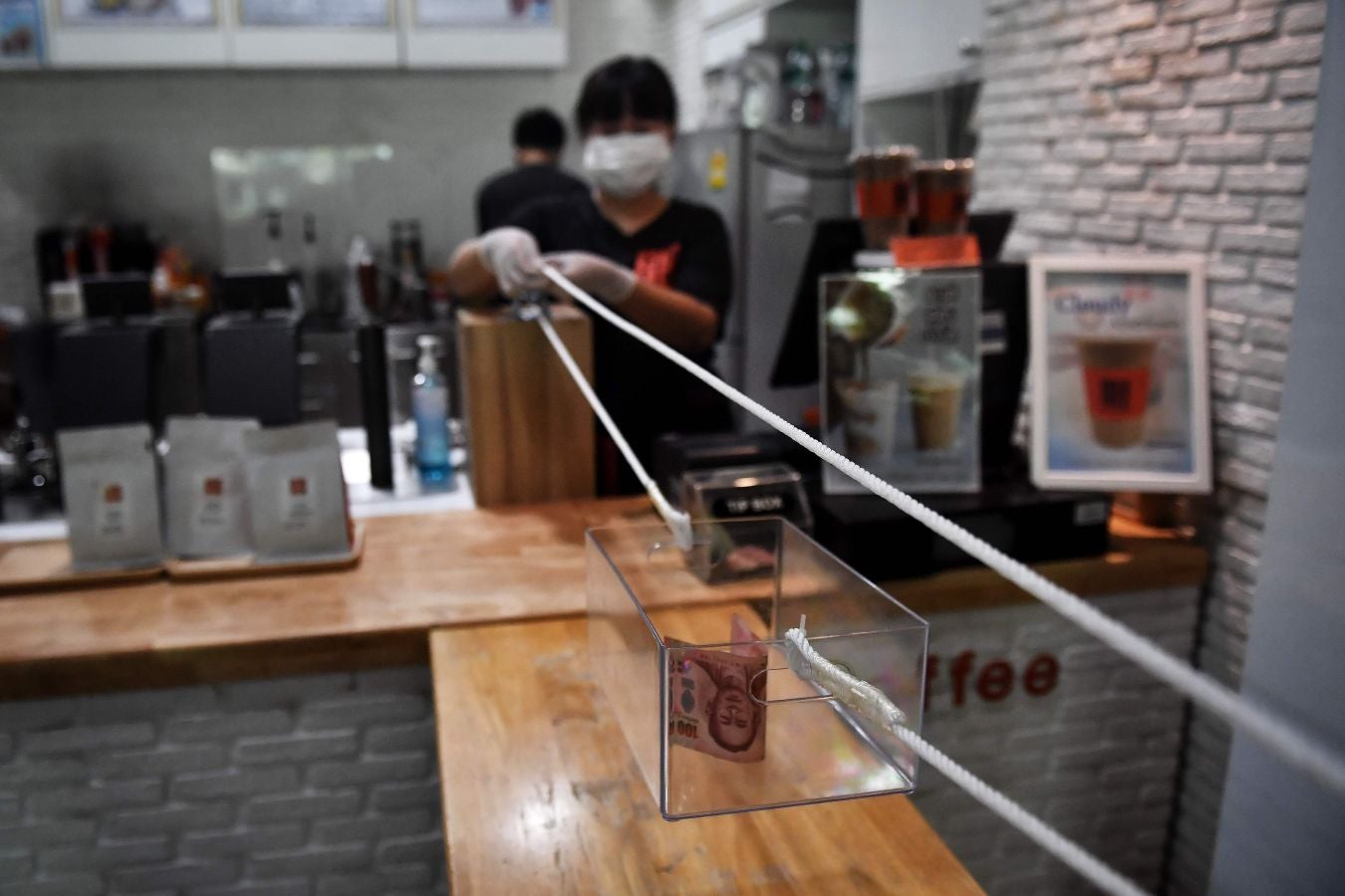 Una cafetería de Bangkok ha ideado este sistema rudimentario a la par de original para que los clientes puedan pagar sus cafés respetando las distancias de seguridad.