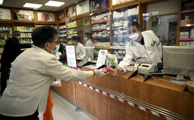 Un farmacéutico entrega a una cliente una mascarillas. 