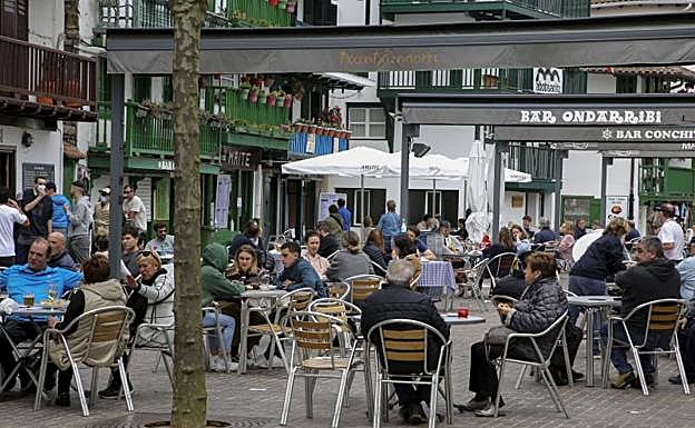 Imagen principal - Arriba: El buen tiempo acompañó y las terrazas de La Marina estuvieron al completo casi todo el día. Izquierda: Desde que el lunes se permitió abrir los veladores, se han ido sumando establecimientos, que han empezado a retomarla actividad. Derecha: En Donostia se permite a algunos hosteleros ampliar el espacio para la terraza, como este, a ambos lados de la carretera.