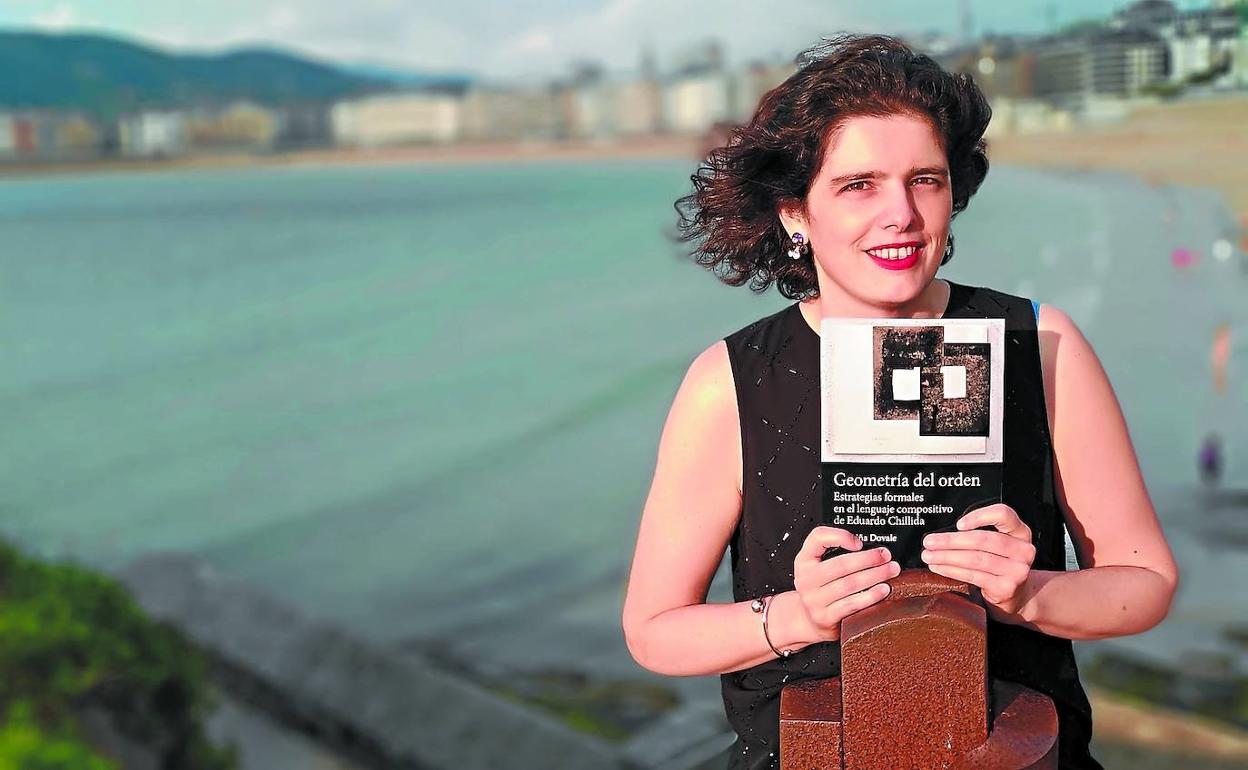Carmiña Dovale, con un ejemplar de 'Geometría del orden', en el Pico del Loro junto a la obra 'Estela a Rafa Balerdi' (1992), de Chillida