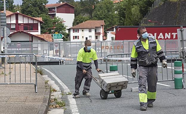 Operarios retiran la valla de hormigón y metálica que hasta ahora cerraba el puente de Behobia y la sustituyen por otra ligera. 