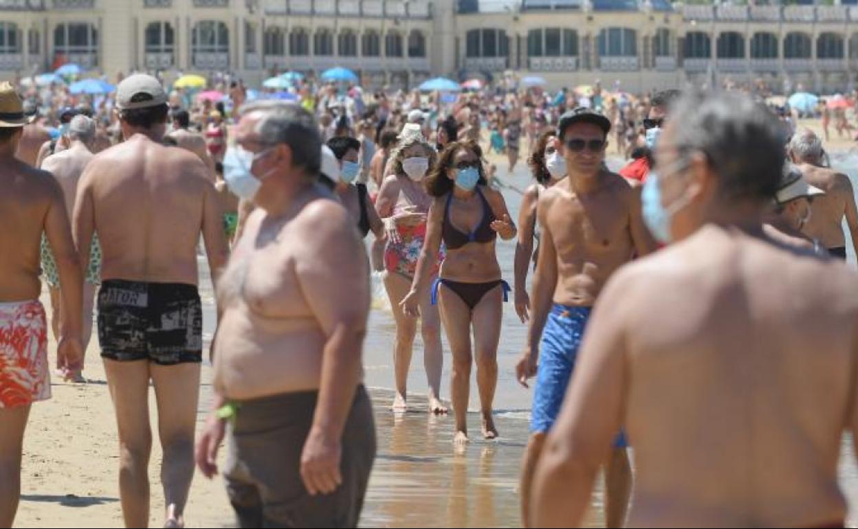 Paseantes en la orilla de La Concha con mascarilla. Hay novedades más importantes, pero esta es simbólica.