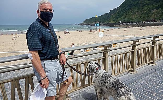 José Luis Arrúe, con mascarilla, pasea con su perro por el paseo de La Zurriola, en Donostia.