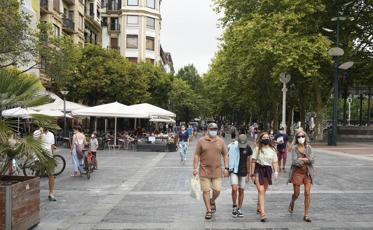 Varias personas paseando un día de agosto por el Boulevard donostiarra. 