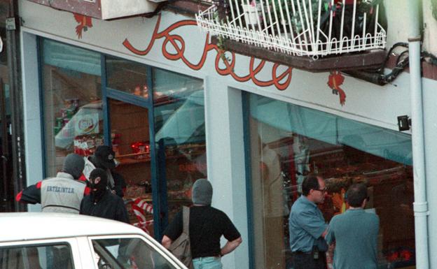 Agentes de la Ertzaintza custodian el exterior de 'Kokolo', la tienda que de golosinas que regentaba Indiano y donde se perpetró el atentado. 